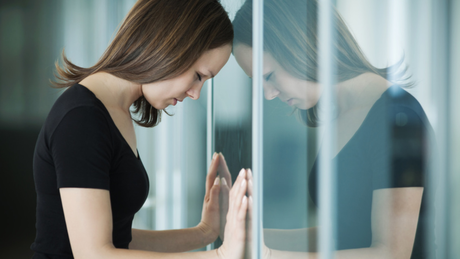 young woman  woman leaned against glass wall in crisis moment