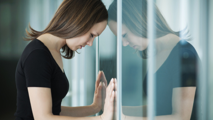 young woman  woman leaned against glass wall in crisis moment